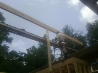 Carpenter setting a ridge beam over a new addition frame — Ice Dam Removal by Roofing Brothers in Fleming