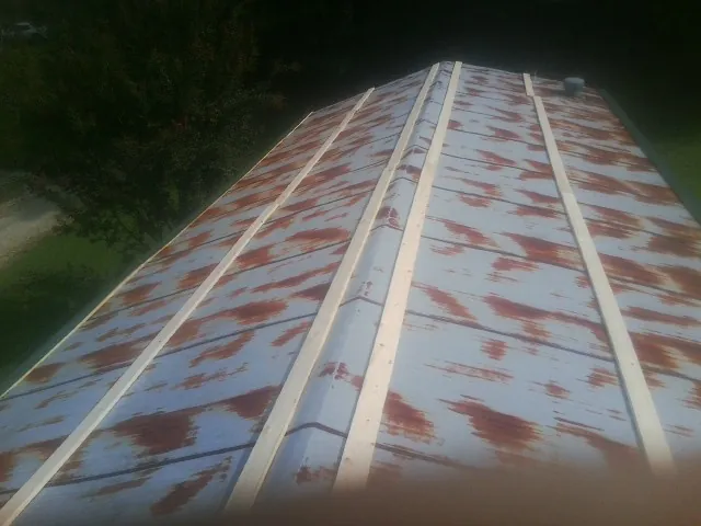 Rusted metal roof panels with new wood purlins before replacement — Storm Damage Roof Repair in Fleming by Roofing Brothers