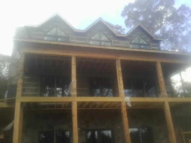 Dormers and porch framing on a large log home under construction — Roof Coating work by our crew in Fleming