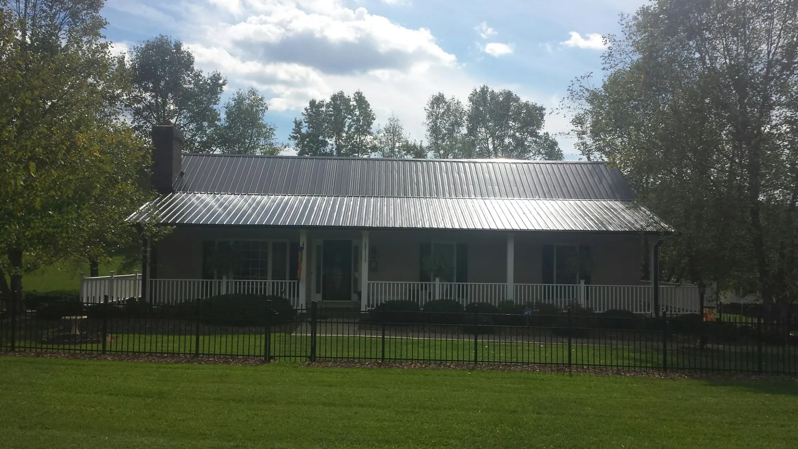 Gray metal roof on a brick ranch with a full width front porch — Gutter Guard Installation work by our crew in Fleming