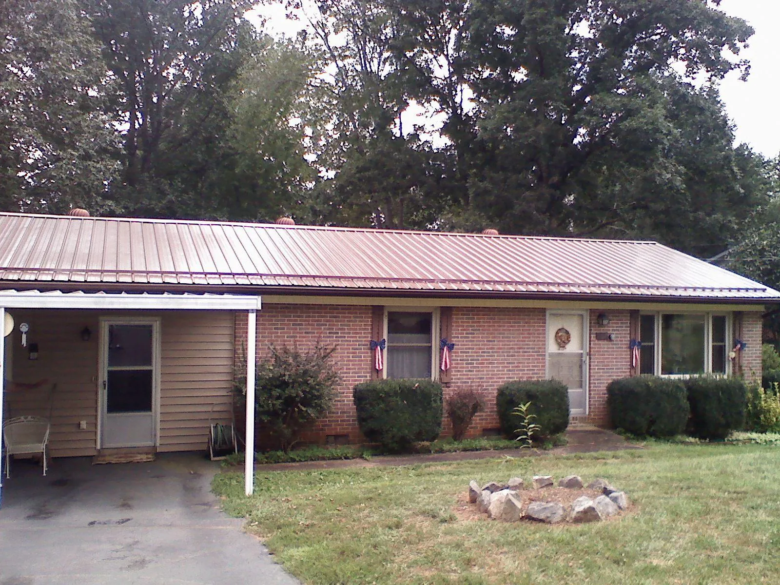 Bronze metal roof and carport on a brick ranch home — Roof Repair work by our crew in Fleming