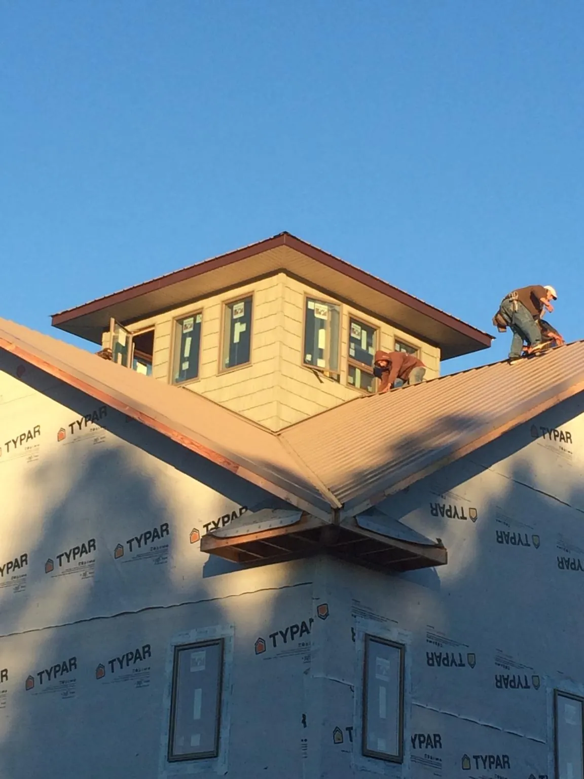 Roofers working around a rooftop cupola on a new metal roof at sunset — Roof Waterproofing in Fleming by Roofing Brothers